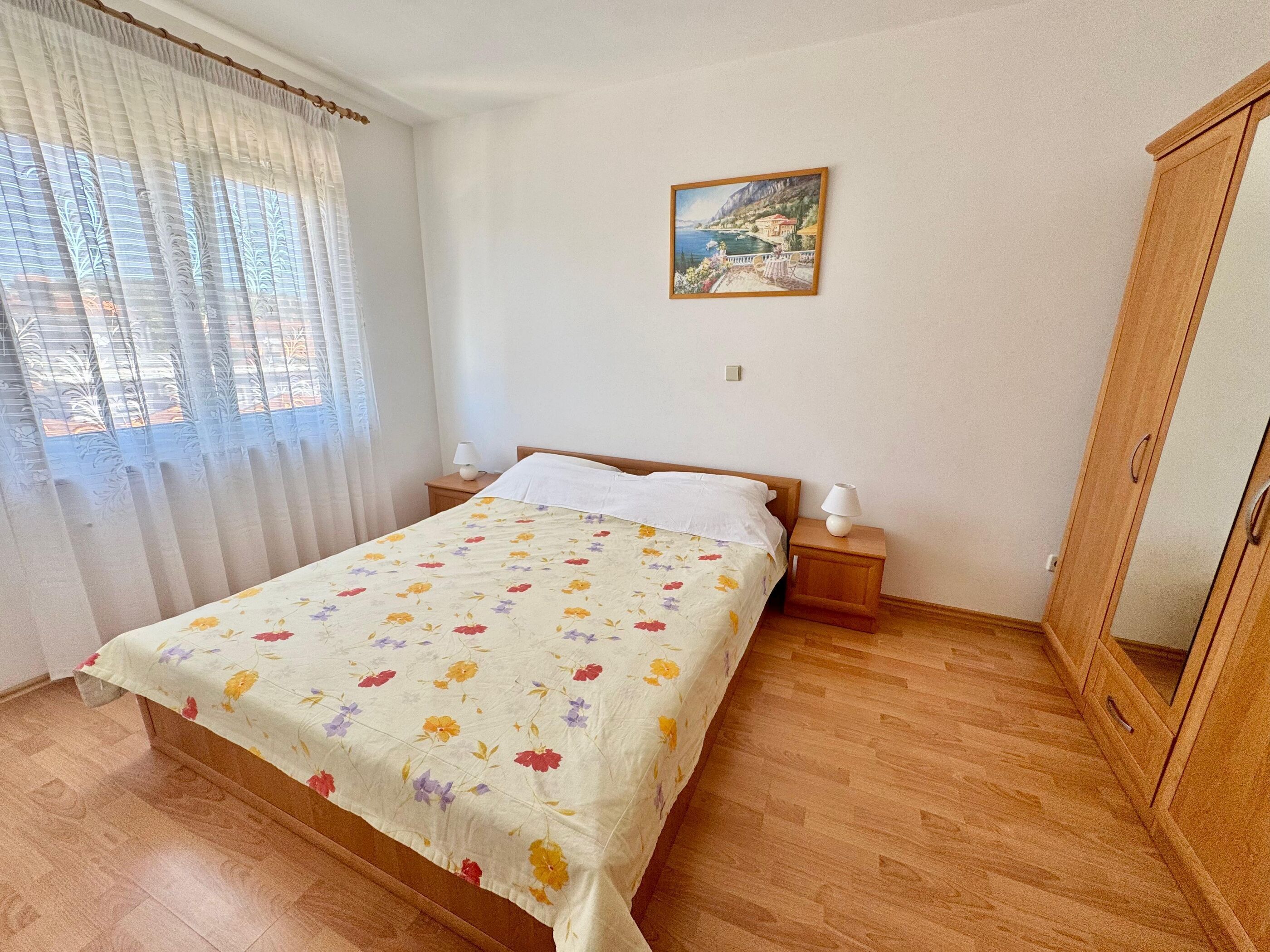 Una camera da letto con un letto, un comodino, una lampada, un quadro appeso e un armadio.
