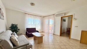A living room with a sofa, a coffee table, a dining table with chairs, and a potted plant. - Apartments Cukon (16136-A7) - Medulin (Medulin)
