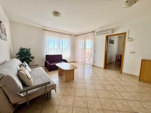 A living room with a sofa, a coffee table, a dining table with chairs, and a potted plant. - Apartments Cukon (16136-A7) - Medulin (Medulin)
