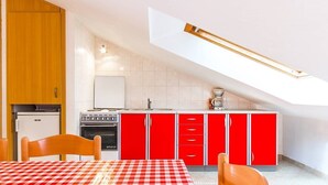A compact kitchen with red cabinets, a white refrigerator, and a checkered tablecloth. - Apartments Cukon (16136-A8) - Medulin (Medulin)