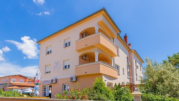A multi-story building with balconies, a clock, and a statue in front. - Apartments Cukon (16136-A8) - Medulin (Medulin)