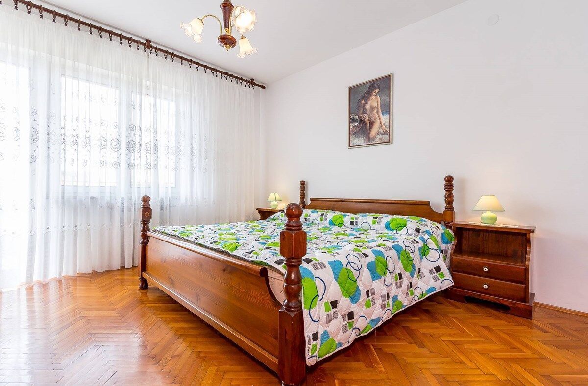 Une chambre à coucher avec un lit en bois, une table de chevet avec une lampe et un tableau accroché au mur.