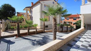 Una zona residenziale con un cortile lastricato, palme e case con tetti in tegole rosse.