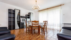 Un soggiorno moderno con un tavolo da pranzo, sedie, un lampadario e un pavimento decorato.