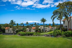 A resort with multiple buildings, a well-maintained lawn, and a view of the ocean. - The Palms at Wailea (Kihei)