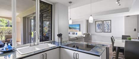 Una cocina moderna con una isla grande, un comedor con mesa y sillas, y vistas al exterior.