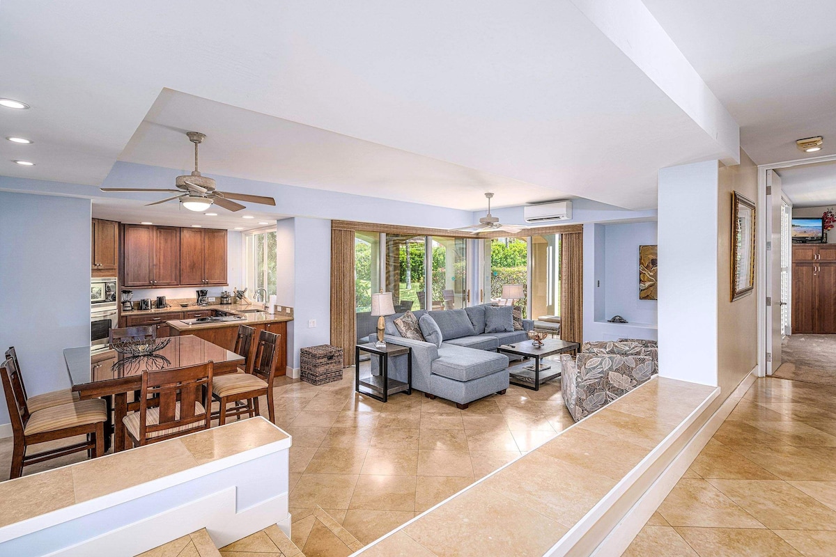 A spacious living area with a dining table, sofas, and a kitchen in the background.