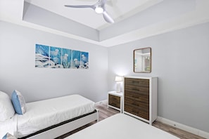 Un dormitorio con cama, mesita de noche, lámpara, cómoda y ventilador de techo.