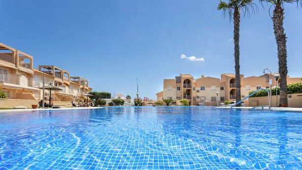A swimming pool with tiled flooring, surrounded by buildings with balconies and palm trees. - cozy Ground-floor apartment 4p terrace pool & parking beach --> 2km (VC)