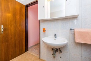 Une salle de bain avec une porte en bois, un lavabo blanc et une serviette rose.