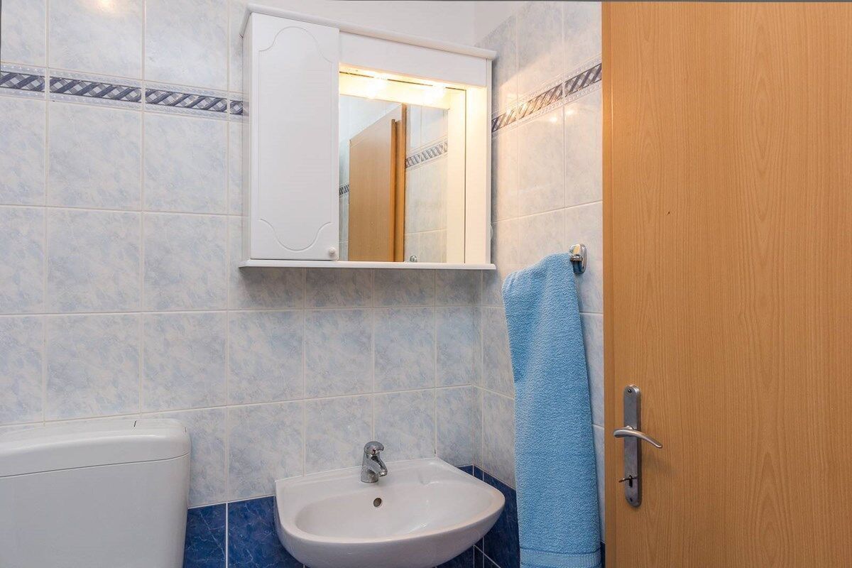 A bathroom with a white sink, a mirror above it, and a wooden door.