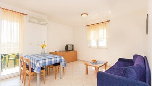 Ein kompakter Wohnraum mit Essbereich, einer Couch, einem Fernseher und einem Tisch mit Früchten.