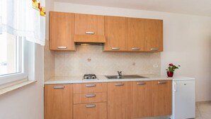 A modern kitchen with wooden cabinets, a built-in gas stove, a sink, and a small refrigerator. - Apartments Verde (16211-A2) - Premantura (Premantura)