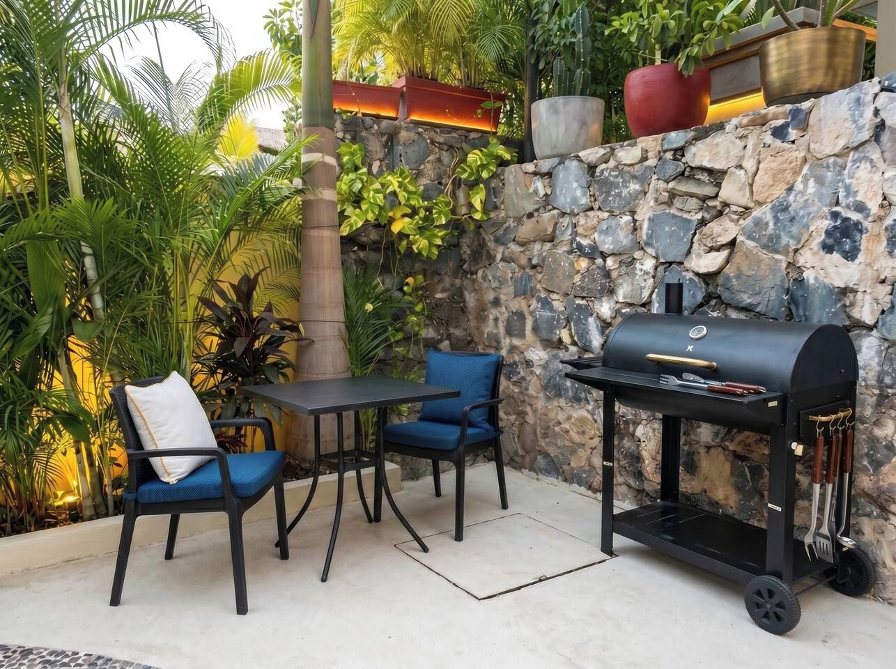 An outdoor patio with a stone wall, a grill, and seating.