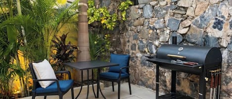 An outdoor patio with a stone wall, a grill, and seating.