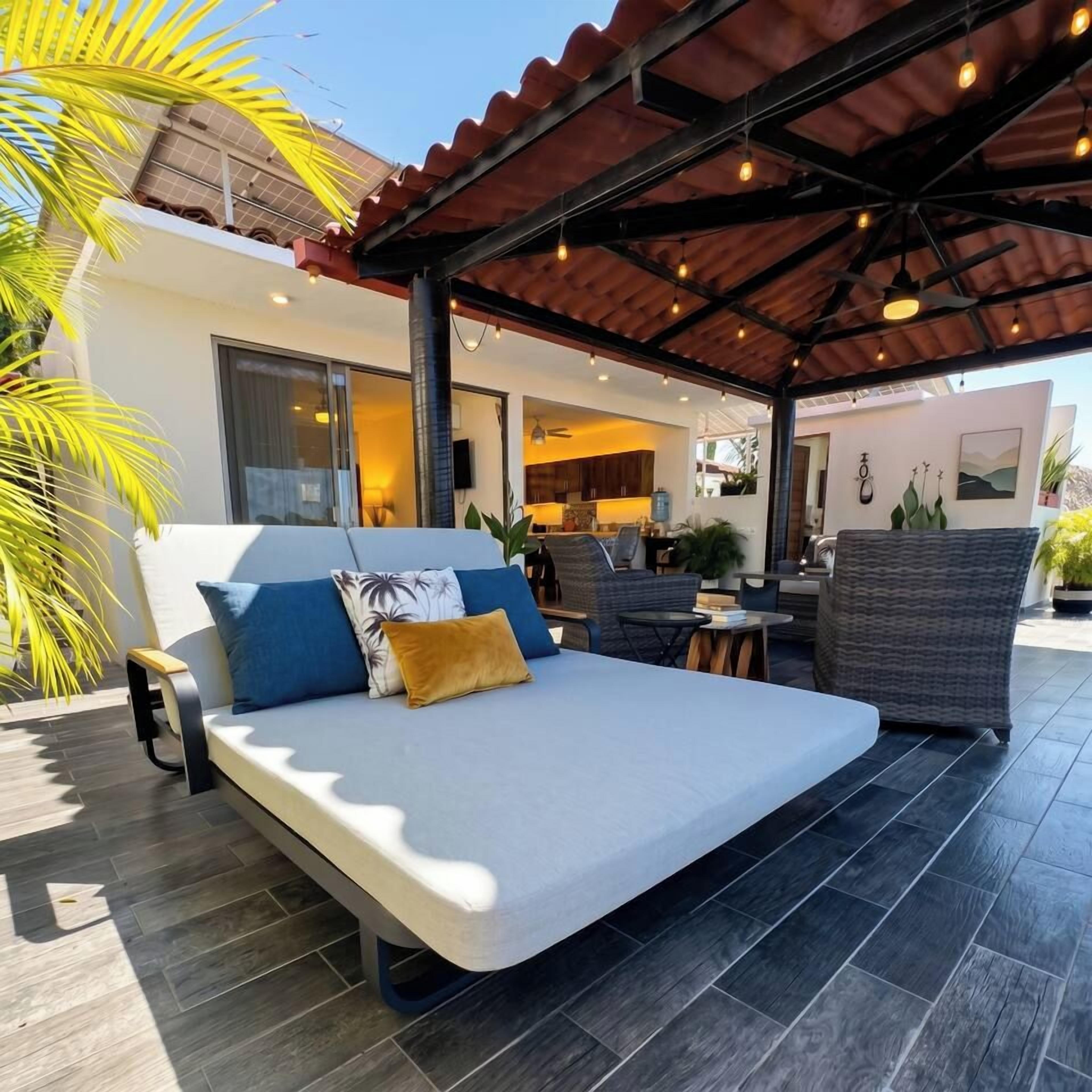 Un espacio exterior moderno con sofá, sillas y una mesa de comedor.