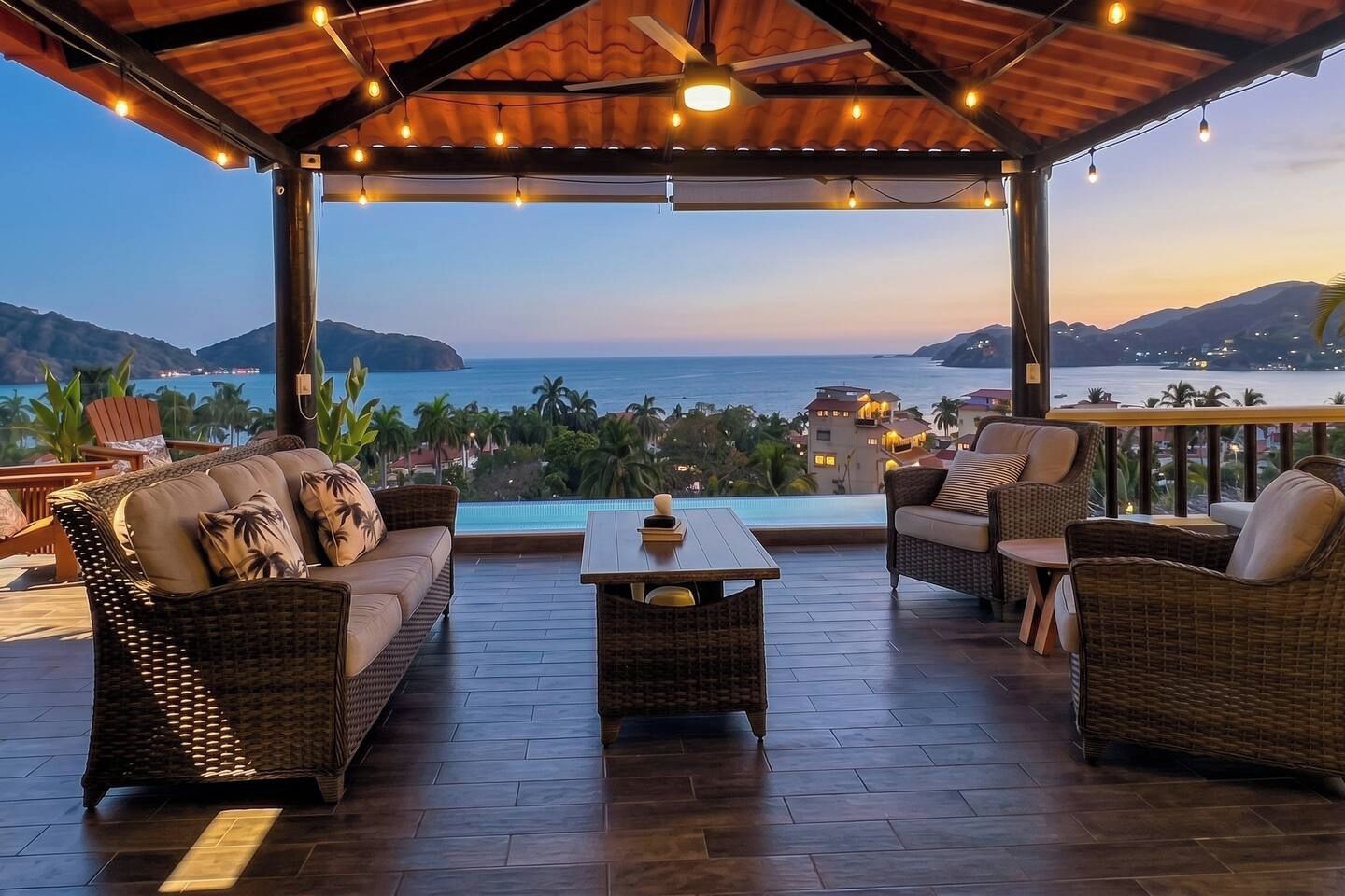 Un espace extérieur aménagé, abrité et doté de mobilier en osier, avec une piscine et une vue sur la mer et les montagnes.