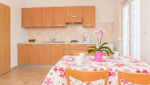 A kitchen with wooden cabinets, a coffee maker, and a dining table with chairs. - Apartments Verde (16211-A5) - Premantura (Premantura)