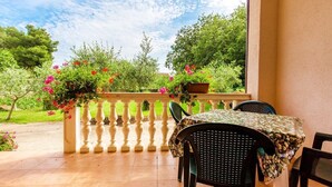 Ein Balkon mit Tisch und Stühlen, umgeben von Blumentöpfen und einem Geländer.