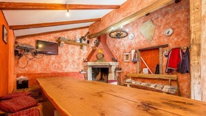 Eine rustikale Küche mit einem Holztisch, einem Kamin und diversen Küchengeräten.