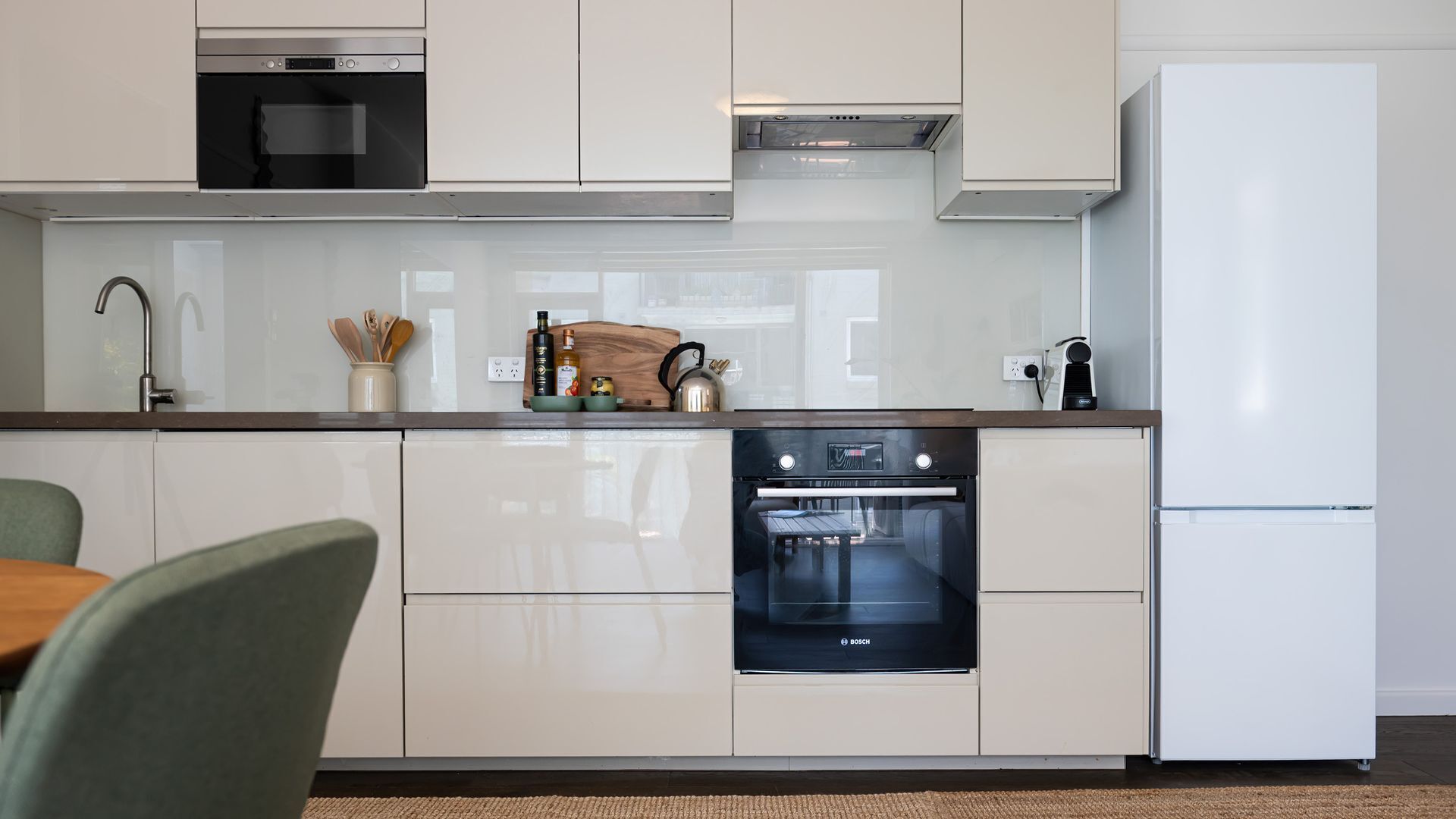 A modern kitchen with white cabinetry, a Bosch oven, and a white refrigerator.