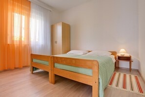 A bedroom with a wooden bed, a wardrobe, a bedside table with a lamp, and a striped rug. - Apartment Ratko (16257-A2) - Medulin (Medulin)