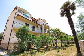 A multi-story building with balconies, a palm tree, and a garden area. - Apartment Ratko (16257-A2) - Medulin (Medulin)