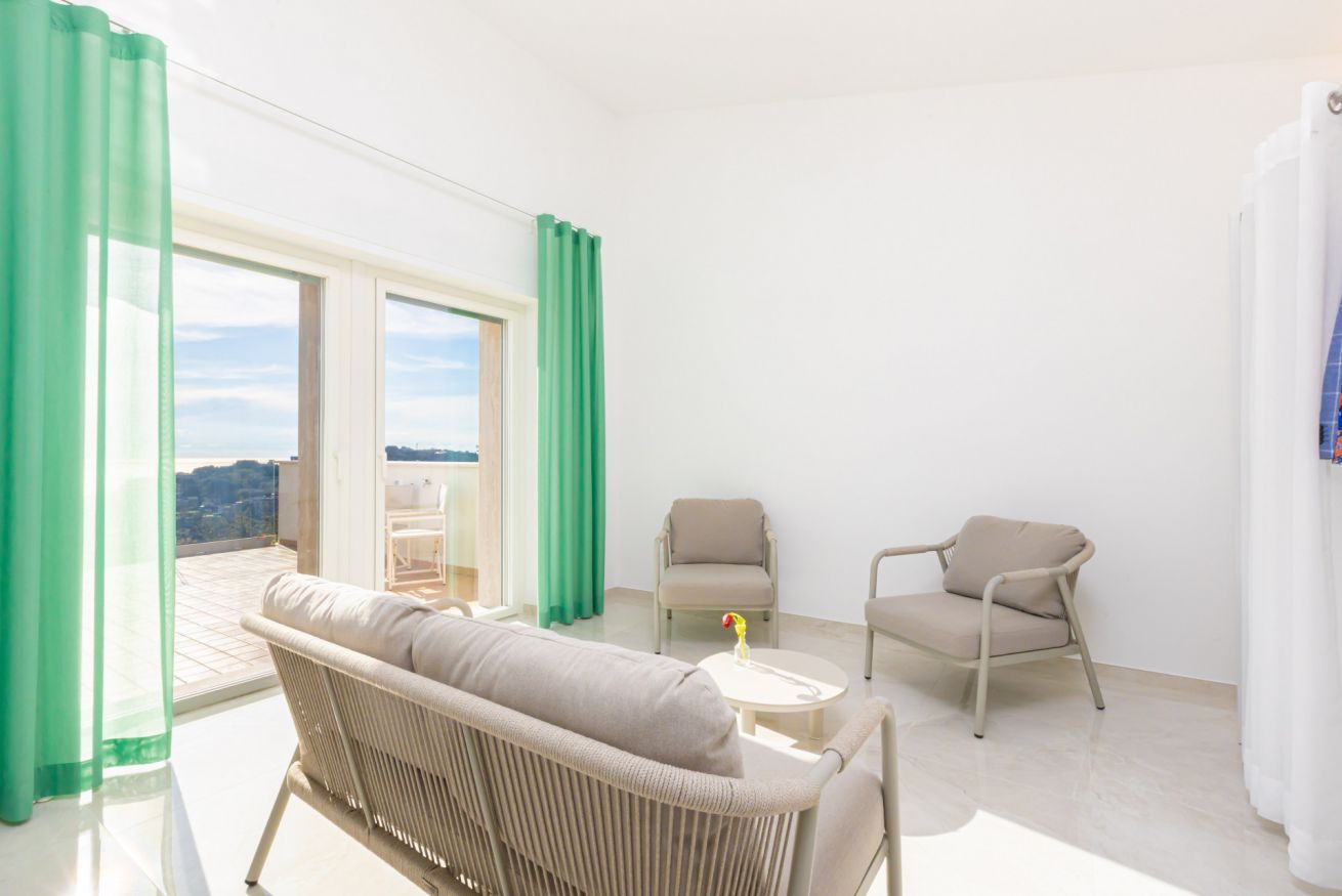 A bright room with a sofa, two chairs, a small table, and a view of the outdoors.