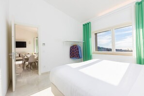A hotel room with a bed, a desk with chairs, a TV, and a window with a view. - Modern Sorrento Coast Villa with Private Pool & Terrace (Massa Lubrense)