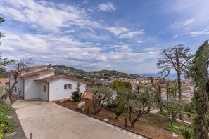 A white building with a tiled roof, surrounded by trees and a clear sky. - Modern Sorrento Coast Villa with Private Pool & Terrace (Massa Lubrense)