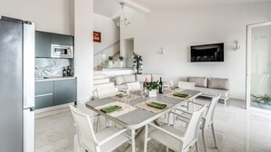 A modern kitchen with a built-in microwave and a dining area with a table set for four. - Modern Sorrento Coast Villa with Private Pool & Terrace (Massa Lubrense)