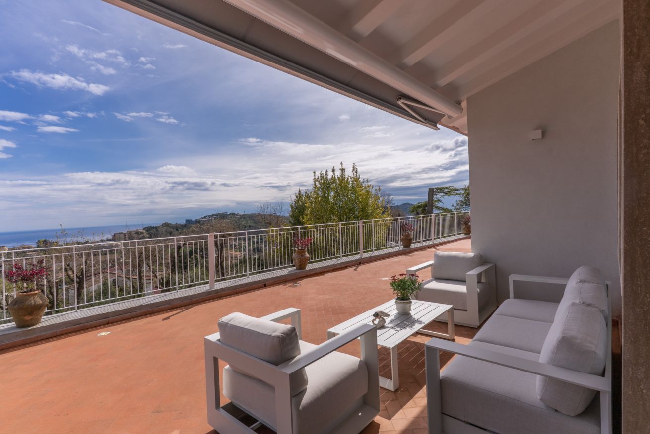 Un balcon avec des meubles blancs, une vue sur la mer et une balustrade blanche.