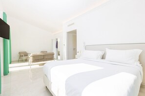 A modern hotel room with a large bed, a sitting area with a chair and a small table, and a view of the outside. - Modern Sorrento Coast Villa with Private Pool & Terrace (Massa Lubrense)