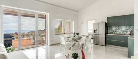 A modern apartment with a dining area, kitchen, and a balcony with a view.
