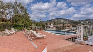 A rooftop pool area with lounge chairs and a swimming pool, surrounded by trees and hills in the background. - Modern Sorrento Coast Villa with Private Pool & Terrace (Massa Lubrense)