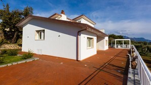 A modern two-story house with a wooden deck and a covered outdoor seating area. - Modern Sorrento Coast Villa with Private Pool & Terrace (Massa Lubrense)