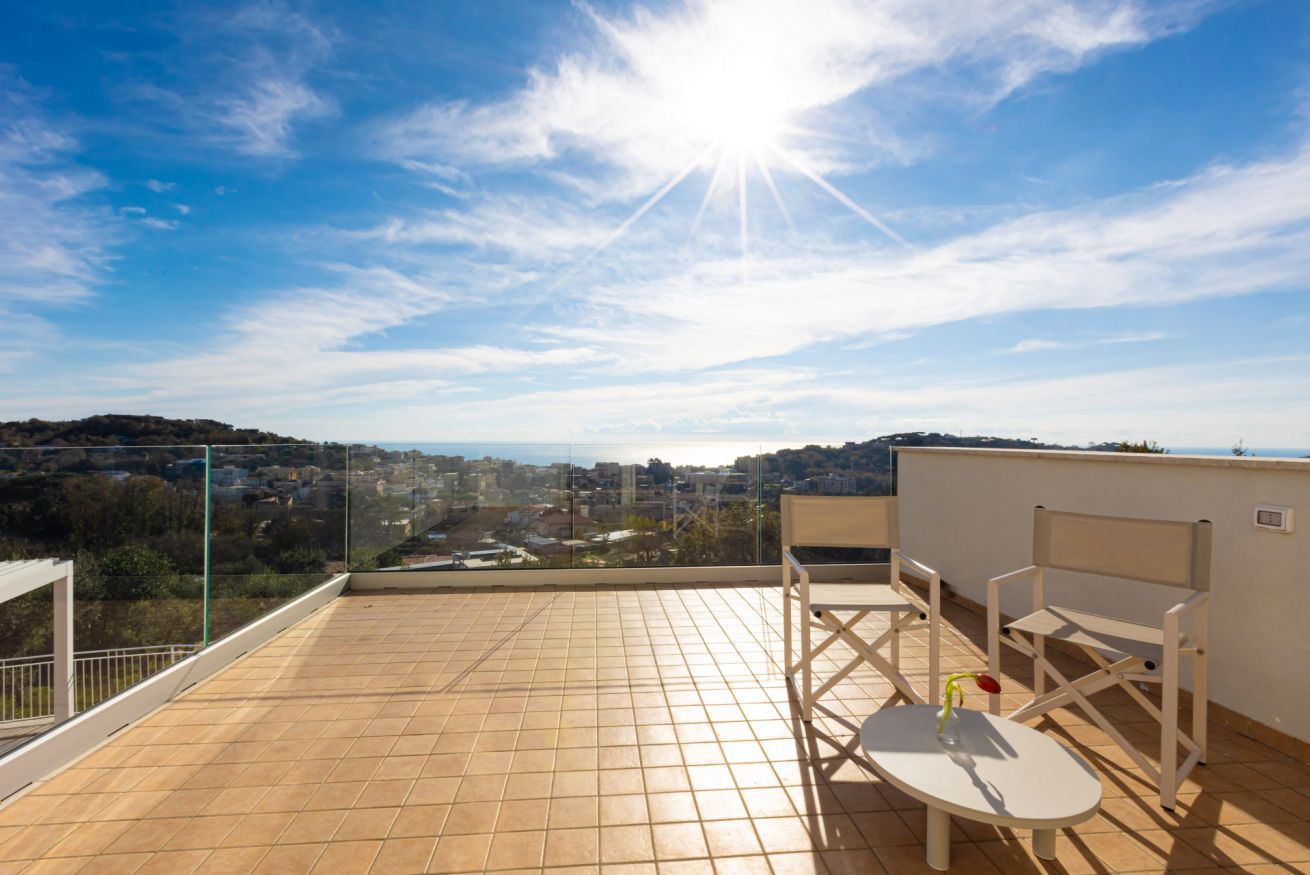 Terraza en la azotea con vistas a un paisaje urbano, dos sillas y una pequeña mesa.