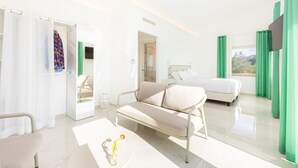 A bright hotel room with a sofa, a bed, a TV, and a view of the outdoors. - Modern Sorrento Coast Villa with Private Pool & Terrace (Massa Lubrense)