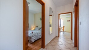 Un pasillo estrecho, con una cama en la habitación de la izquierda y una zona de comedor en la derecha.