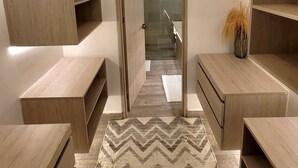 A modern bathroom with wooden shelving, a shower area, and a patterned rug. - Personal Jacuzzi•Beach •Pool•Personal Concierge (La Boquilla)