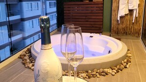 A modern indoor setting with a hot tub, a bottle of champagne, and two wine glasses on a round table. - Personal Jacuzzi•Beach •Pool•Personal Concierge (La Boquilla)