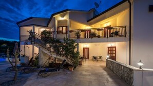 Uma casa de dois andares com varanda, área de estar externa e escada que leva ao andar superior.