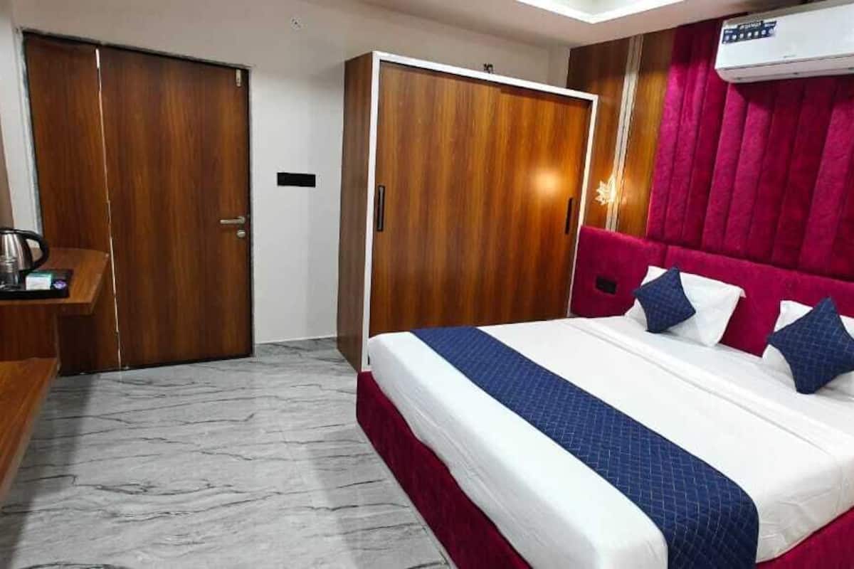 Quarto de hotel com cama, televisão, guarda-roupa e uma parede decorada em vermelho.
