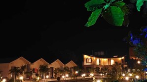 Un hotel con varias edificaciones, cada una con un estilo arquitectónico diferente. Los edificios están iluminados, lo que sugiere que es de noche.