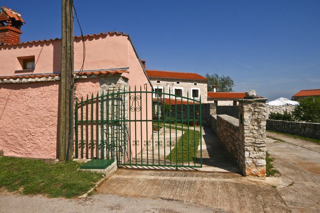 Un edificio rosa con un muro in pietra e un cancello verde.