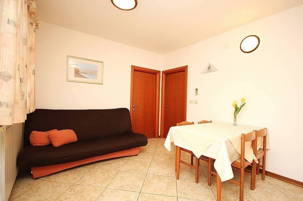 A room with a dark brown sofa, a dining table with a white tablecloth, and two wooden doors.