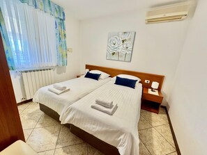 A double bed with white linens, a wooden headboard, a nightstand with a lamp, and a radiator. - Apartments Ladonia (16296-A2) - Krnica (Pula) (Krnica (Pula))