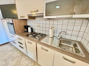 A modern kitchen with a gas stove, a built-in oven, a coffee maker, and a stainless steel sink. - Apartments Ladonia (16296-A2) - Krnica (Pula) (Krnica (Pula))