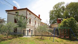 Un edificio de dos pisos con balcón, un columpio y un patio cercado.