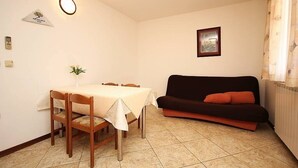 Un área de comedor con una mesa y sillas, un sofá negro y un cuadro en la pared.